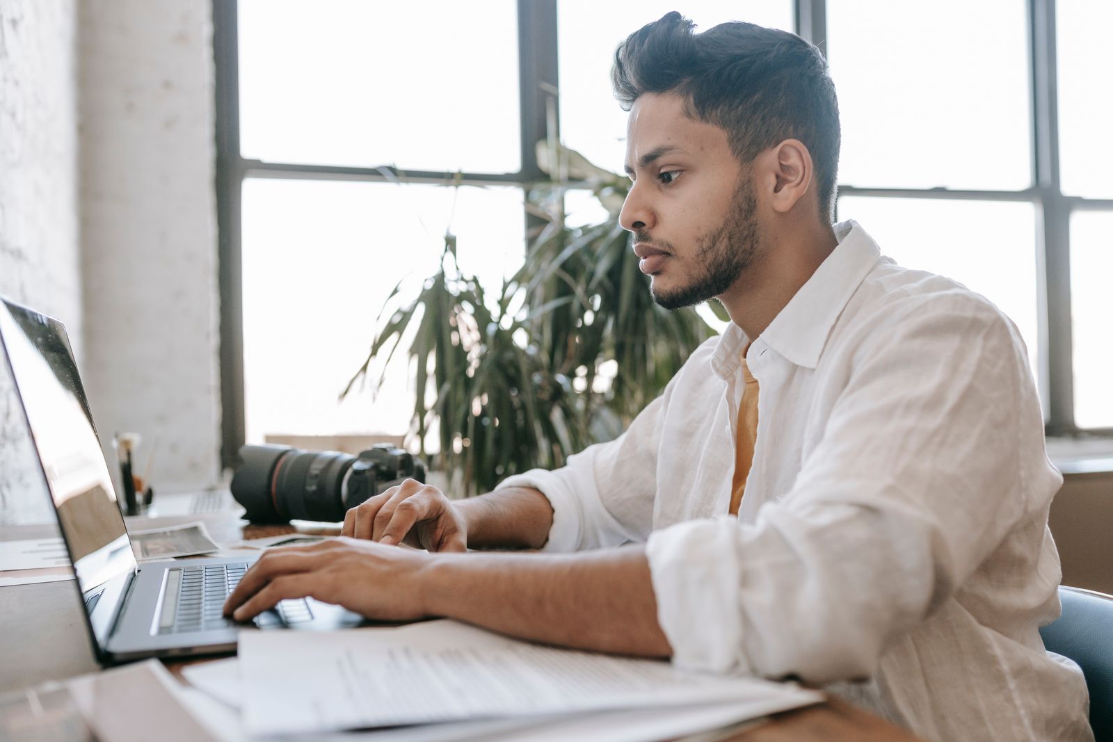 A person working at a laptop by a window